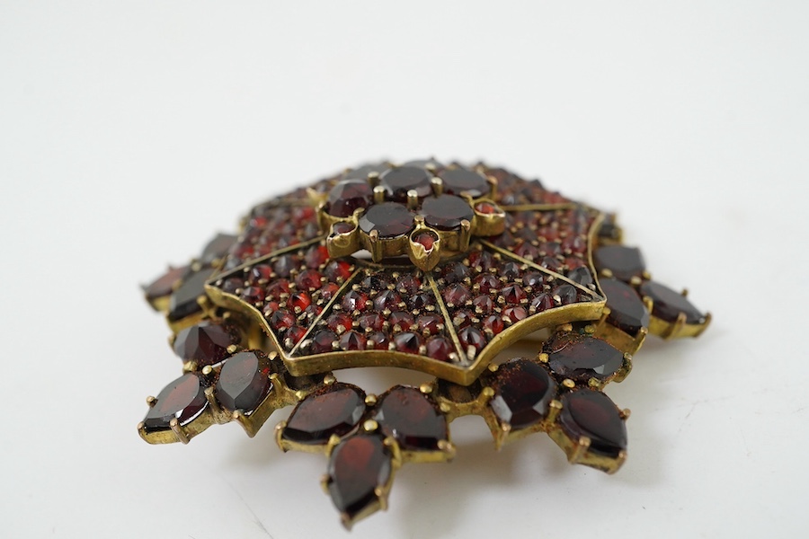 A Victorian style yellow metal and garnet cluster set snow flake brooch, 41mm. Condition - fair